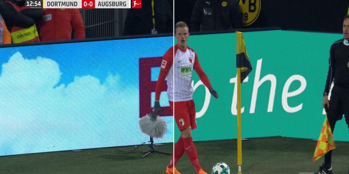 Augsburg player prepares for a corner kick against Dortmund with dynamic digital ads displayed on the perimeter boards.